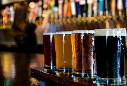 A flight of 4 craft beers lined up on the bar.