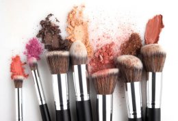 Creative concept beauty fashion photo of cosmetic product make up brushes kit with smashed lipstick eyeshadow on white background.